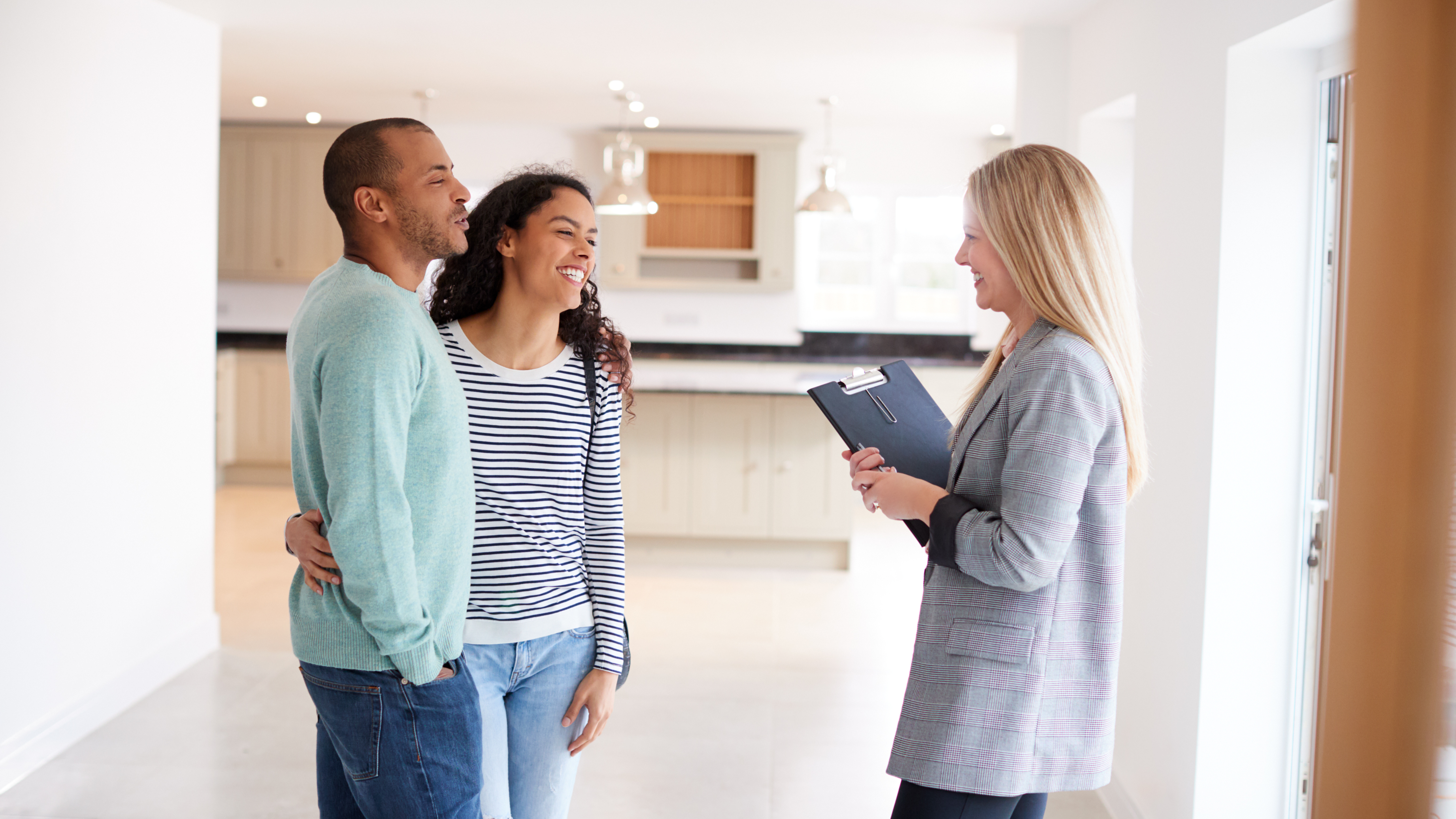 Zwei Personen die mit einer Maklerin sprechen. Sie stehen ein einem Einfamilien Haus und wissen mit ob sie das Haus Minen oder Kaufen wollen